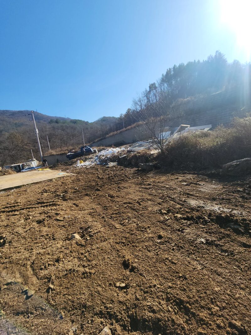 용인판넬창고철거 현장 - 장비 바퀴 자국이 남은 흙바닥과 멀리 판넬 잔재가 보이는 부지 진입 구간