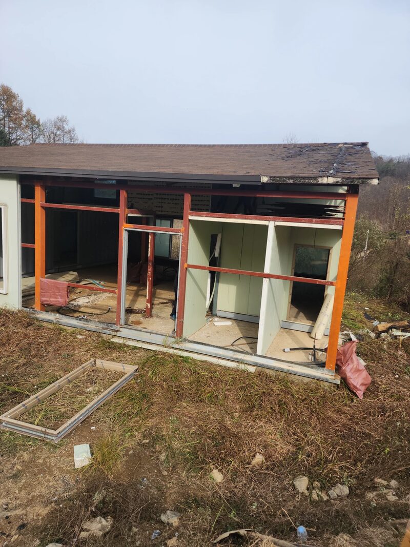 성남판넬창고철거 현장 - 주황색 철골과 창호 칸막이가 남아 있는 구조물과 바닥에 분리되어 놓인 창틀